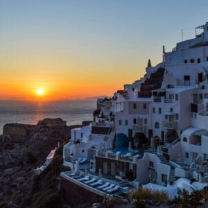 Stunning sunset over the iconic white buildings of Santorini, Greece, with a view of the Aegean Sea.